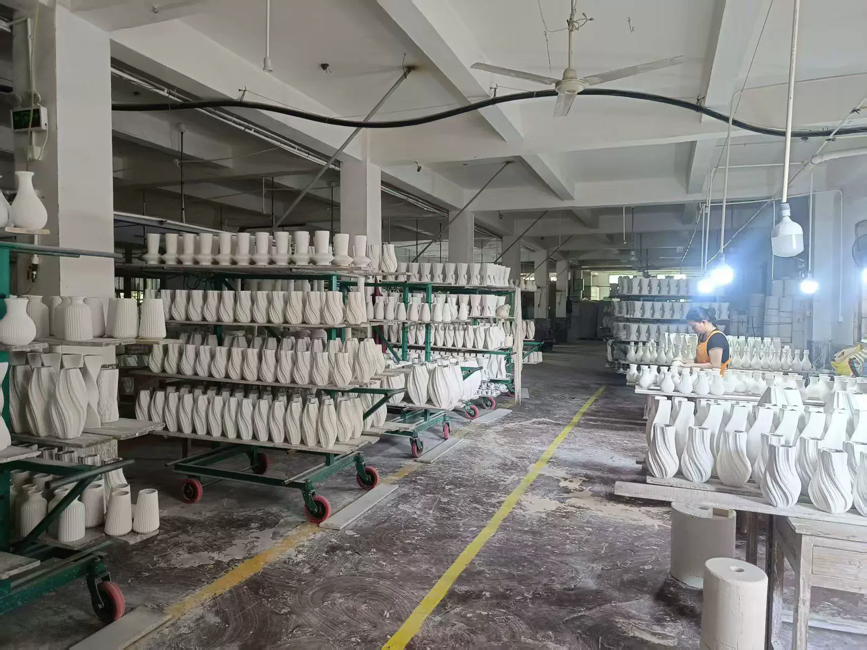 Dehua craft floor — kiln carts of spiral porcelain and artisan finishing at the workbench