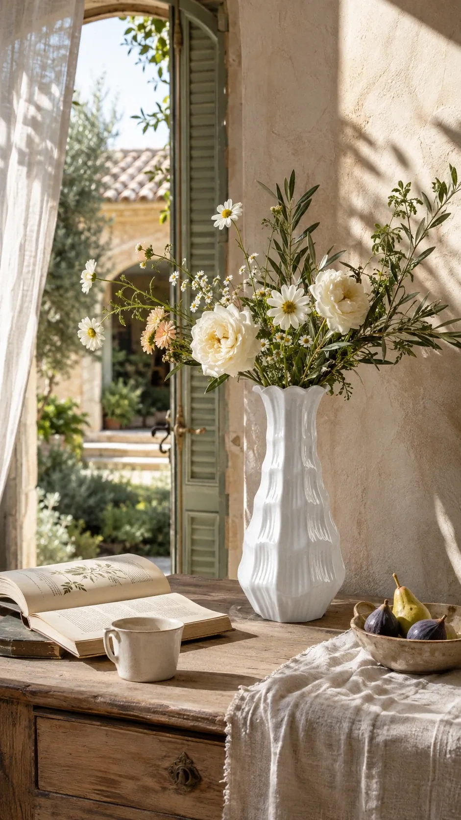 Lunara Blanc Petal Vase on a Provençal courtyard table with white blooms, figs, and arched shutter light